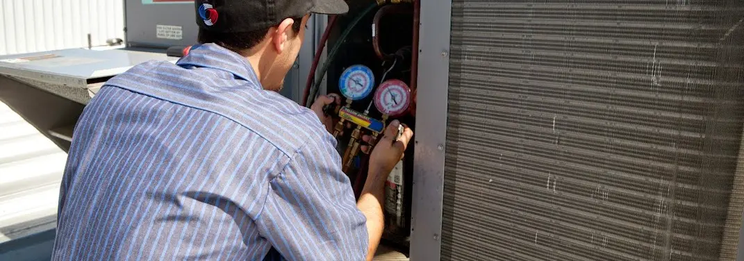 HVAC technician servicing a condenser unit in Tisbury